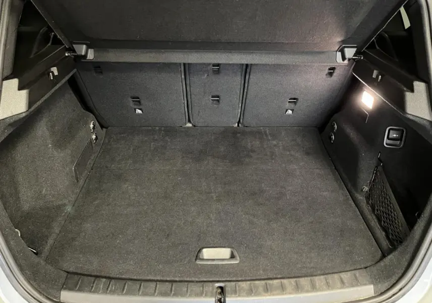 Coffre ouvert de la BMW Série 2 225xe Active Tourer gris, montrant l'espace de chargement intérieur avec éclairage latéral.