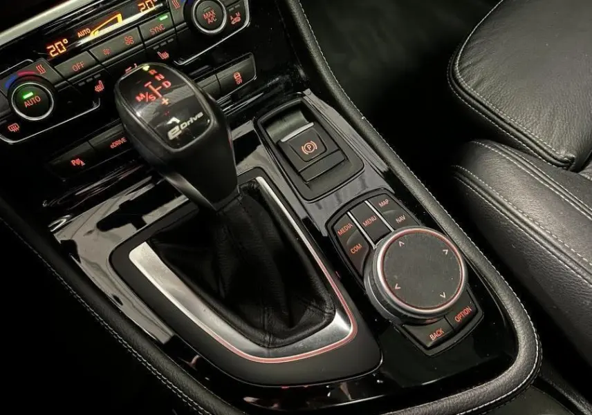 Gros plan sur la console centrale noire de la BMW Série 2 225xe Active Tourer avec levier de vitesses eDrive et commandes multimédia.