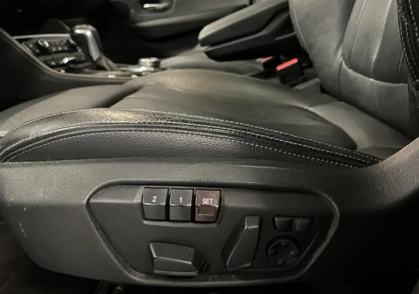 Détail des commandes électriques du siège conducteur en cuir noir dans une BMW Série 2 225xe Active Tourer gris.