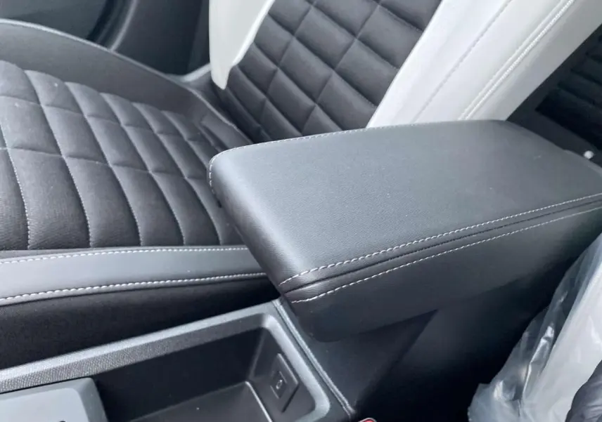 Gros plan sur l'accoudoir central noir et la sellerie bicolore noire et blanche du Citroën C3 Aircross 2025.