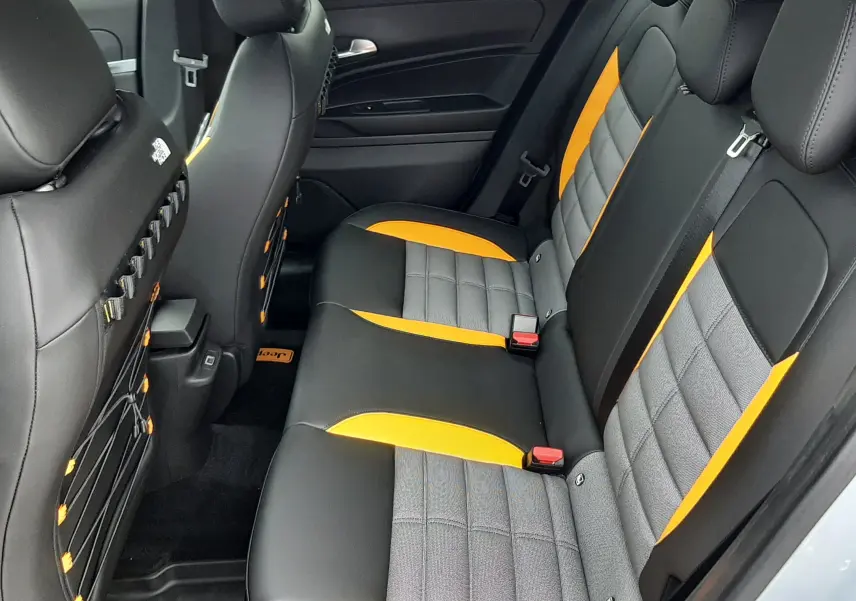 Vue intérieure arrière du Jeep Avenger 2025, sièges noirs avec inserts gris et touches jaunes contrastantes.