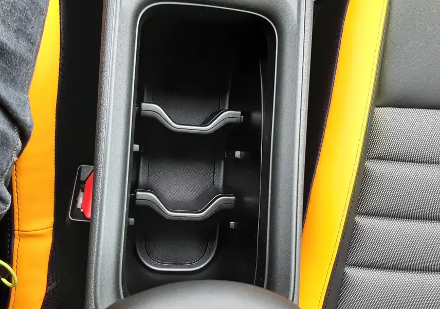 Gros plan intérieur sur le rangement central et les sièges noirs avec surpiqûres jaunes du Jeep Avenger 2025.