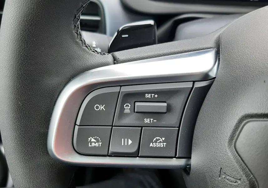 Gros plan sur les commandes au volant côté gauche du Jeep Avenger 2025, finition Storm Grey avec insert argenté.