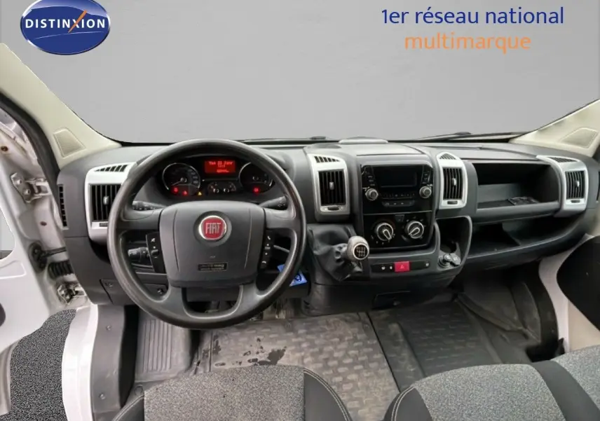 Vue intérieure du tableau de bord du Fiat Ducato Fourgon blanc de 2014, avec volant multifonction et levier de vitesses manuel.
