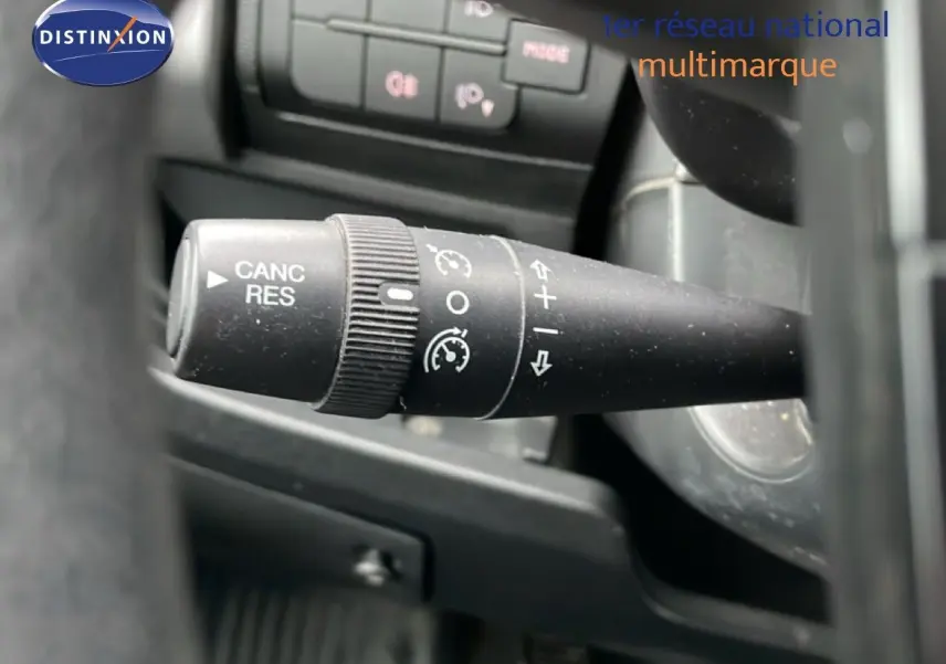 Gros plan sur la commande de régulateur de vitesse noire à gauche du volant du Fiat Ducato Fourgon blanc.