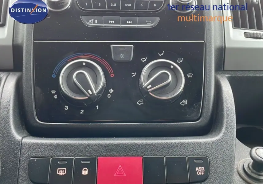 Gros plan sur la console centrale du Fiat Ducato Fourgon 2014, montrant les commandes de climatisation et les boutons de sécurité.