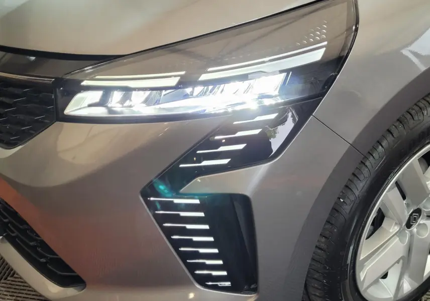 Gros plan sur l'avant droit gris foncé de la Renault Clio 2025 avec phares LED allumés et jante visible.