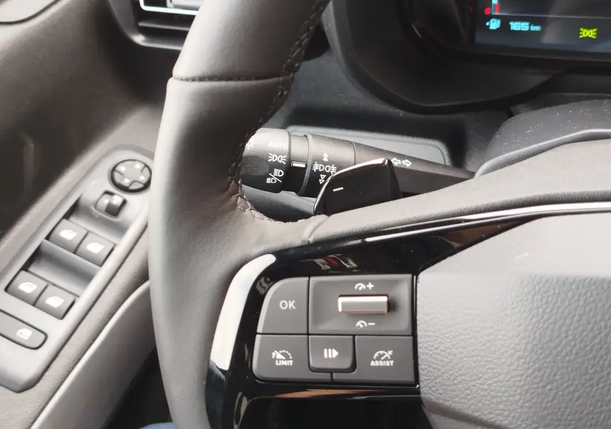 Gros plan sur le volant et les commandes à gauche du tableau de bord d’un Citroën Berlingo 2025, intérieur gris.