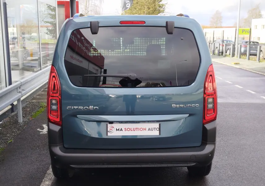 Vue arrière d'un Citroën Berlingo bleu Kiarma 2025 avec vitres teintées et feux arrière verticaux allumés.