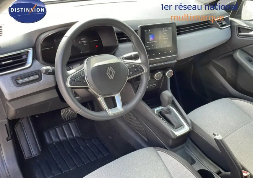 Vue intérieure de la Renault Clio 2025 gris schiste métal, volant cuir multifonction et console centrale avec boîte auto.