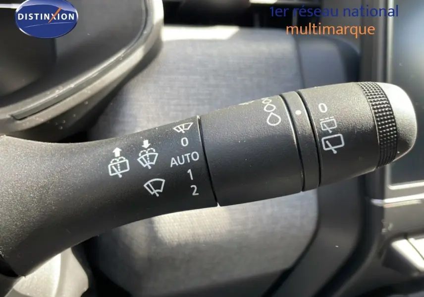 Gros plan sur la commande d’essuie-glace de la Renault Clio 2025, intérieur gris et noir, détails des symboles blancs visibles.