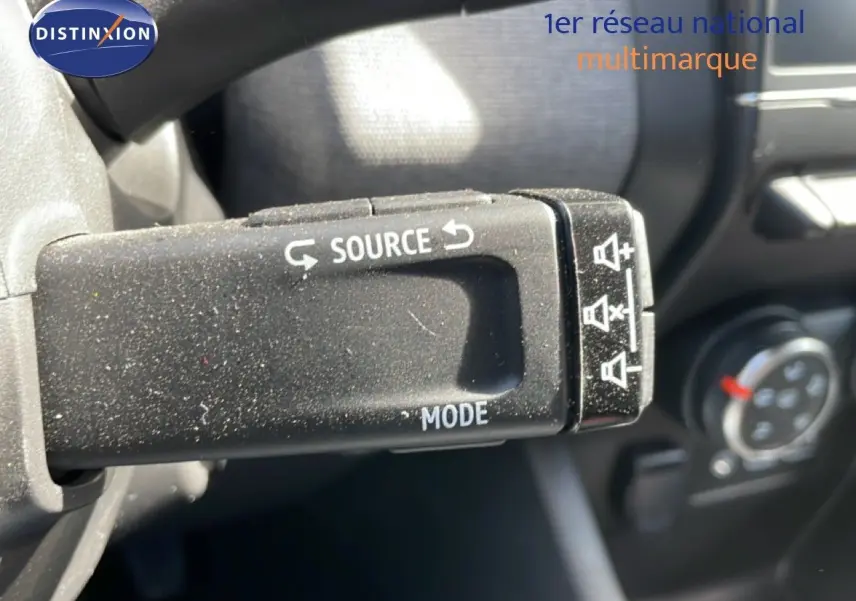 Gros plan sur la commande au volant de la Renault Clio 2025, finition gris schiste métal, avec boutons source et mode visibles.