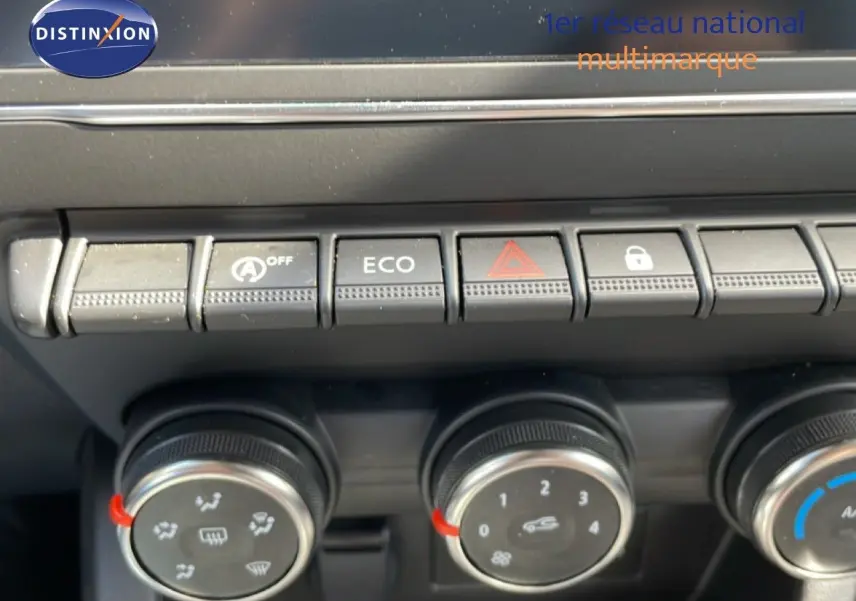 Gros plan sur les commandes de climatisation et boutons fonctionnels du tableau de bord d’une Renault Clio gris schiste.