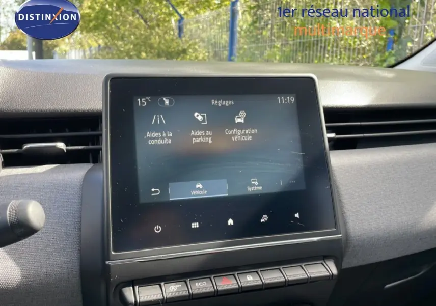 Vue intérieure centrée sur l'écran tactile du tableau de bord de la Renault Clio gris schiste, avec commandes et aérateurs visibles.