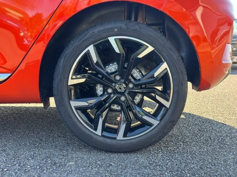 Gros plan sur la roue avant droite noire et argentée de la Renault Clio orange Valencia, avec jante alu au design moderne.