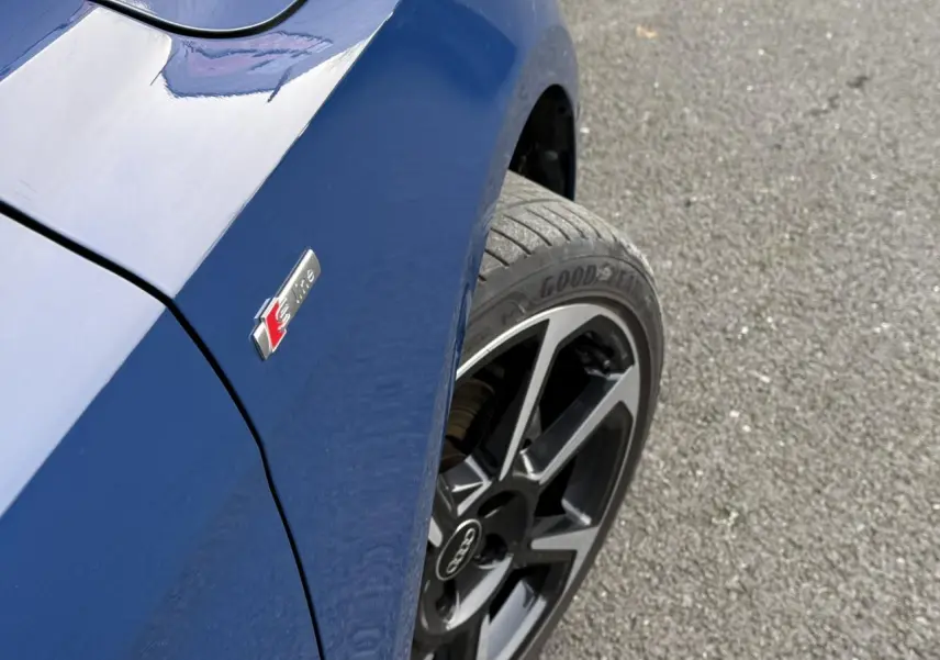 Gros plan sur l'aile avant gauche bleu Ascari d'une Audi A1 Sportback 30 TFSI avec badge S line et jante noire 18 pouces.