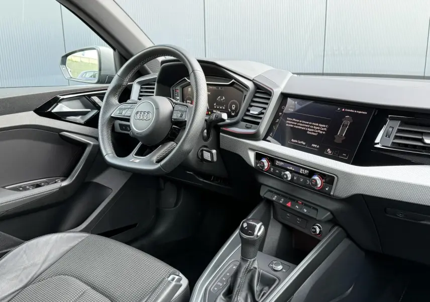 Intérieur avant de l'Audi A1 Sportback 30 TFSI bleu Ascari, volant cuir sport, tableau de bord numérique et écran tactile.