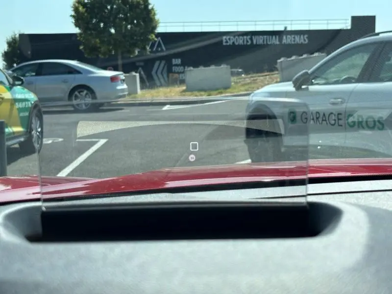 Vue depuis l'intérieur de la Citroën C4 X rouge Elixir, avec affichage tête haute transparent sur le tableau de bord.