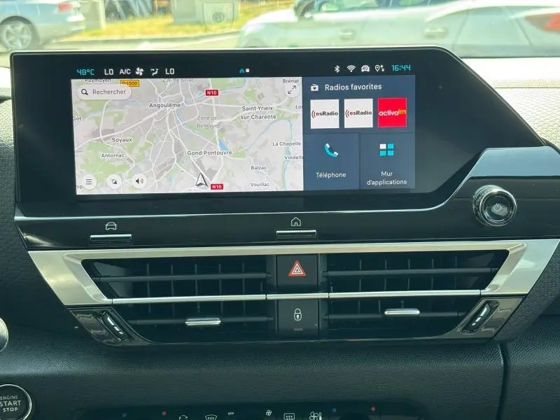 Tableau de bord de Citroën C4 X 2024 avec écran tactile affichant GPS et radios favorites en vue frontale.