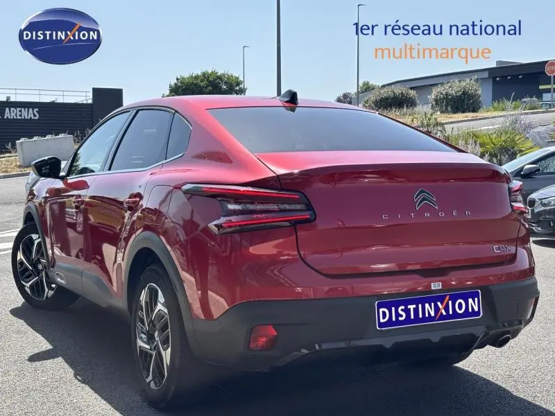 Vue 3/4 arrière droite d'une Citroën C4 X rouge Elixir avec feux arrière LED et jantes alliage visibles