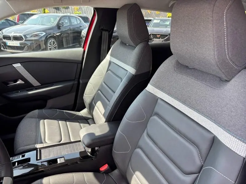 Gros plan sur les sièges avant en textile gris et cuir noir de la Citroën C4 X rouge Elixir, intérieur lumineux.
