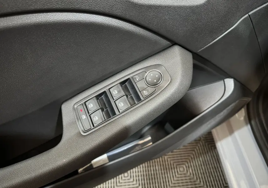 Détail des commandes des vitres électriques sur la porte avant gauche d'une Renault Clio gris clair 2025.