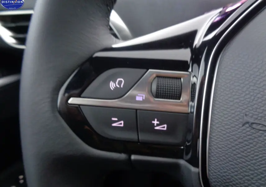 Gros plan sur les commandes du volant noir du Peugeot 3008 2023, avec boutons de volume et téléphone éclairés.