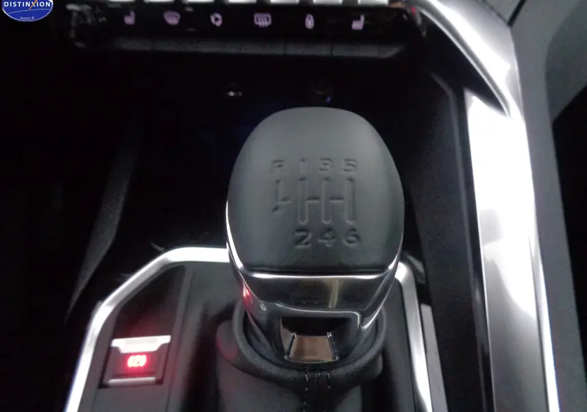 Gros plan sur le levier de vitesse manuel noir du Peugeot 3008 2023, entouré de finitions chromées et boutons lumineux.