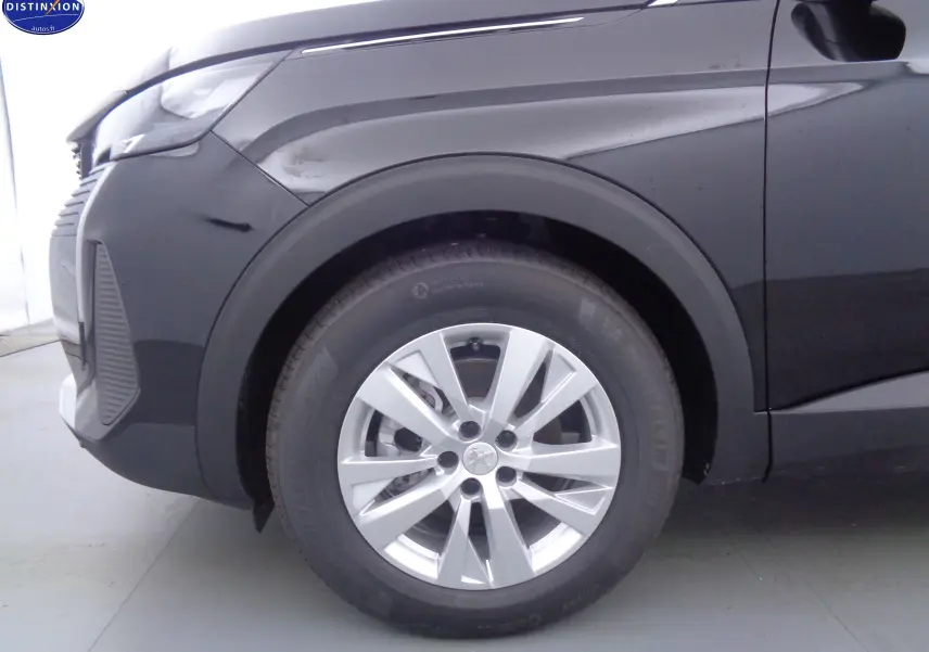 Gros plan sur la roue avant gauche d'un Peugeot 3008 noir perle métal, mettant en valeur la jante argentée et le passage de roue.