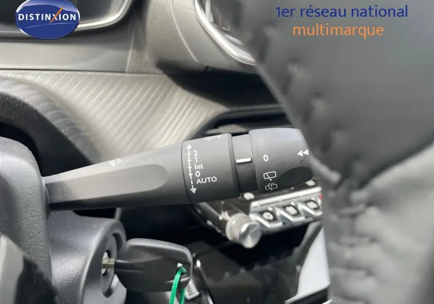 Gros plan sur la commande d’essuie-glace à gauche du volant d’une Peugeot 208 jaune Agueda Metal, intérieur noir.