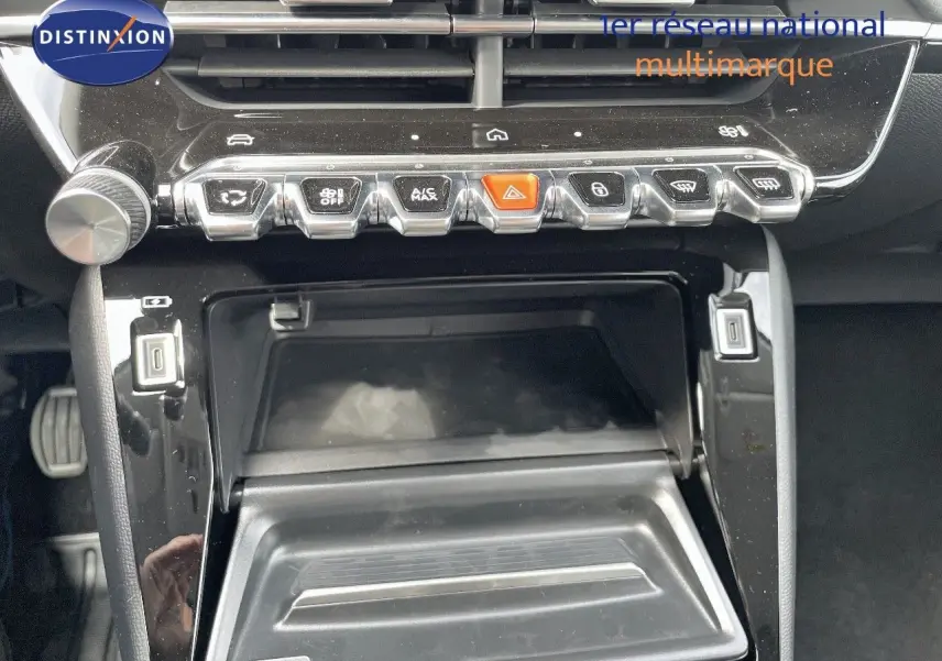 Vue rapprochée de la console centrale noire brillante avec commandes et compartiment ouvert d'une Peugeot 208 jaune Agueda Metal.