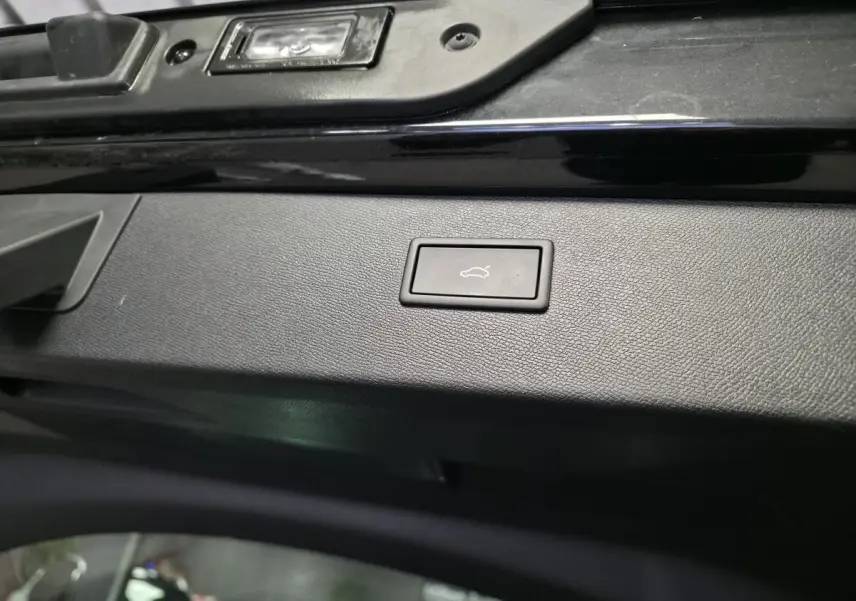 Bouton d'ouverture électrique du hayon sur la partie intérieure noire du coffre d'un CUPRA Formentor noir.