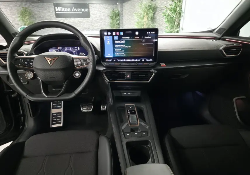 Vue intérieure avant du CUPRA Formentor noir, tableau de bord avec écran tactile central et volant sport multifonction.