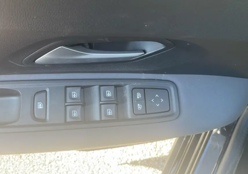 Gros plan sur la commande des vitres électriques et rétroviseurs côté gauche d'une Dacia Jogger noir nacré 2024.