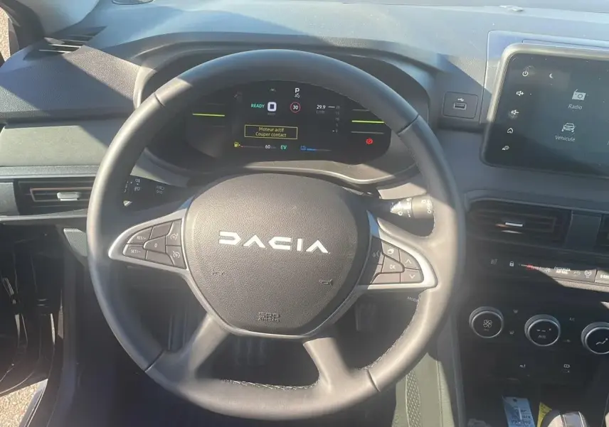 Vue frontale du volant noir du Dacia Jogger 2024 avec tableau de bord numérique et écran tactile central.