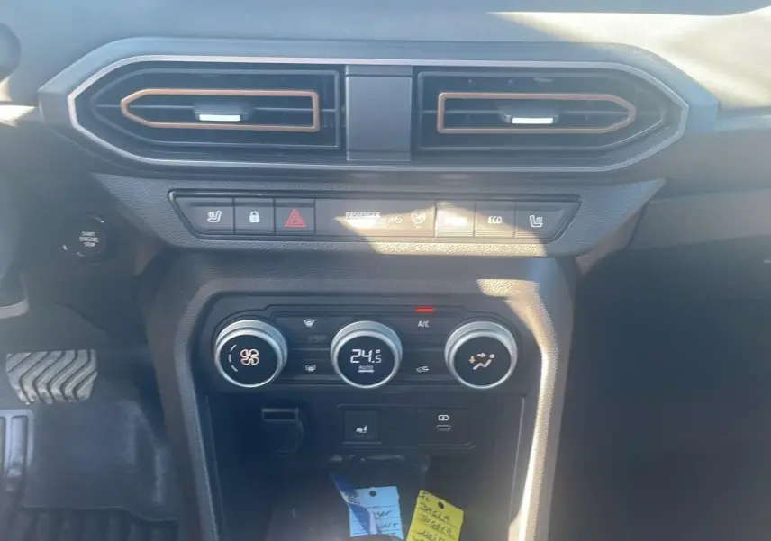 Tableau de bord central du Dacia Jogger 2024 avec commandes climatisation et boutons fonctionnels en vue frontale rapprochée.