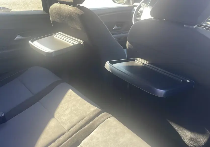 Vue intérieure arrière du Dacia Jogger 2024 avec tablettes rabattables sur les dossiers des sièges avant et banquette 3 places grise.