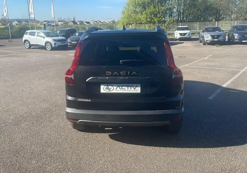 Vue arrière d'un Dacia Jogger noir nacré 2024 avec feux arrière verticaux et logo Dacia lumineux.