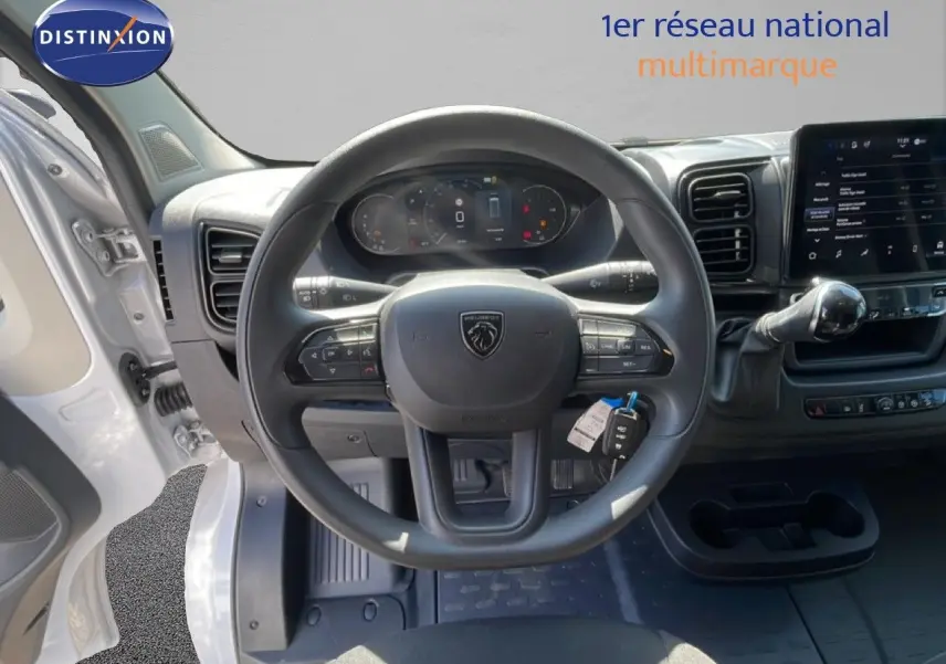 Vue intérieure centrée sur le volant Peugeot d’un Boxer Fourgon blanc banquise avec tableau de bord numérique et écran tactile.