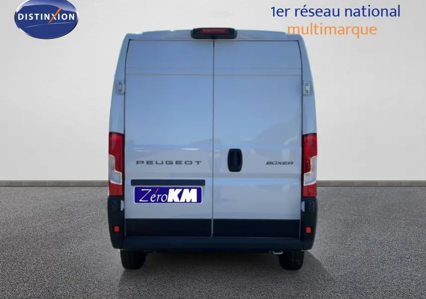 Vue arrière d’un Peugeot Boxer Fourgon blanc banquise, portes fermées, avec logo et plaque Zero KM visibles.