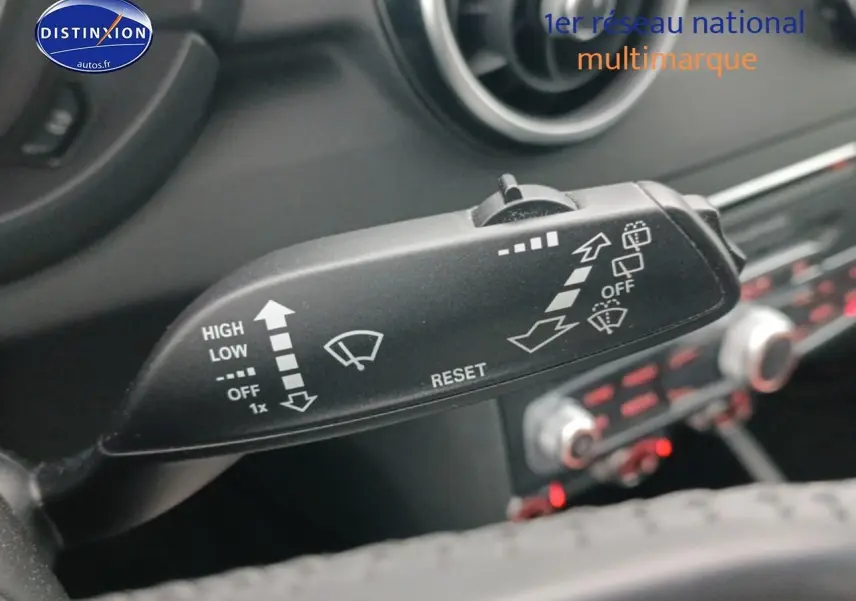 Gros plan sur la commande d’essuie-glace dans l’habitacle d’une Audi A1 blanche, tableau de bord en arrière-plan flou.