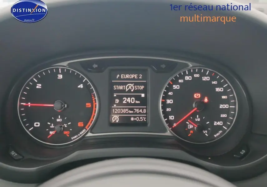 Vue rapprochée du tableau de bord de l'Audi A1 blanc 2015, affichant compteurs et écran multifonction digital.