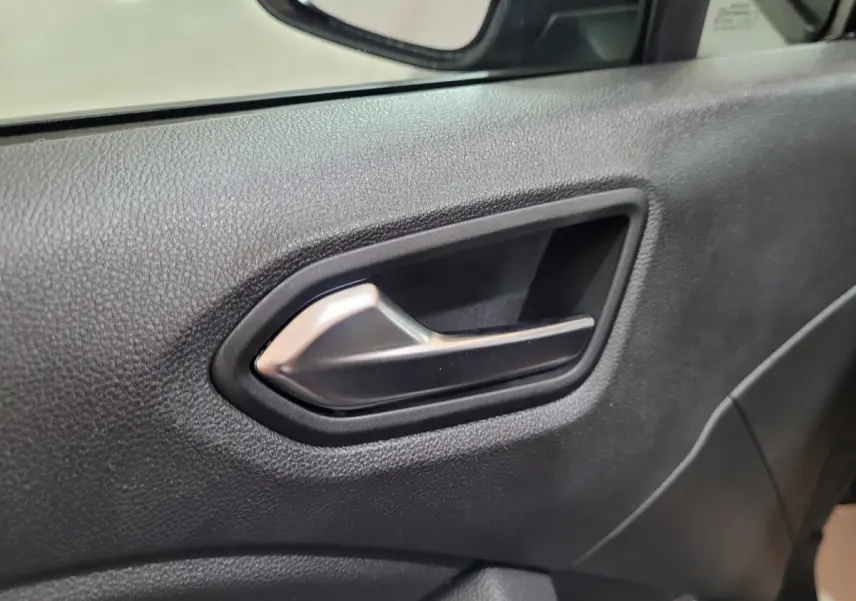 Poignée intérieure de porte côté conducteur de Renault Clio gris foncé, avec texture noire et miroir partiel visible.