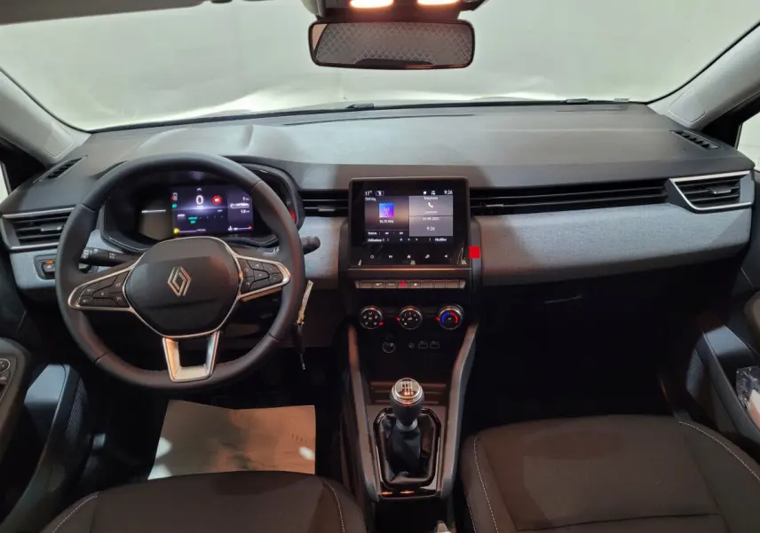 Vue intérieure avant de la Renault Clio gris foncé 2025, volant cuir multifonctions et écran tactile central visible.