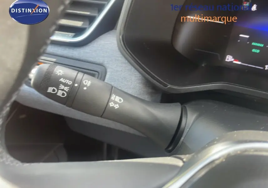 Gros plan sur la commande des phares et clignotants à gauche du volant dans l’habitacle d’une Renault Clio blanche 2025.