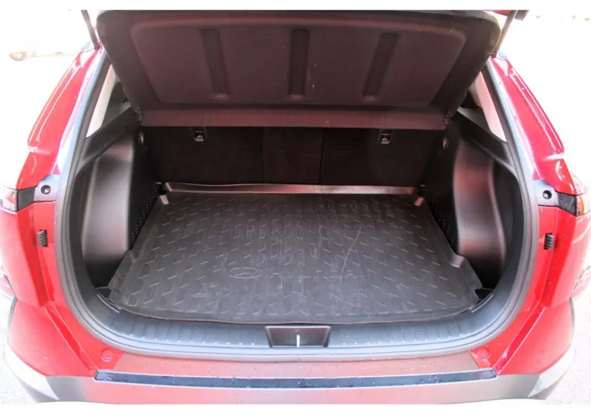 Coffre ouvert vu de l'arrière d'un Hyundai Kona rouge Ultimate Metal avec tapis de coffre noir et seuil de chargement visible.