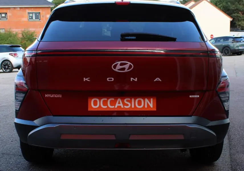 Vue arrière d’un Hyundai Kona rouge Ultimate Metal avec toit noir, badge hybride et plaque « Occasion » visible.