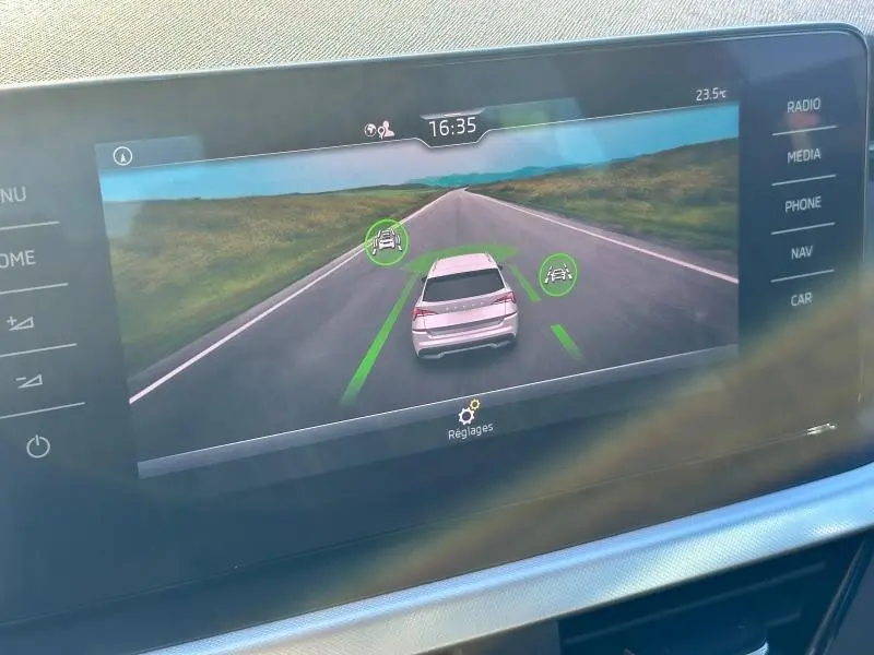 Affichage de l'écran multimédia montrant une vue arrière virtuelle d'un Skoda Kamiq blanc sur route droite.