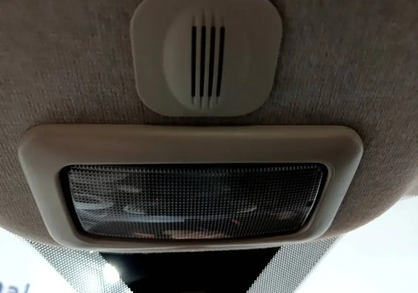Gros plan sur la lumière intérieure et le plafonnier beige du toit d'une Fiat 500 noire vue de l'intérieur.