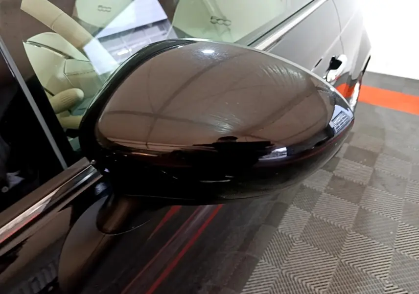 Rétroviseur côté gauche noir brillant d'une Fiat 500 Lounge 2019, avec intérieur beige visible en arrière-plan.